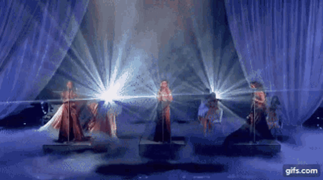 a group of women are singing on a stage with a gifs.com watermark at the bottom