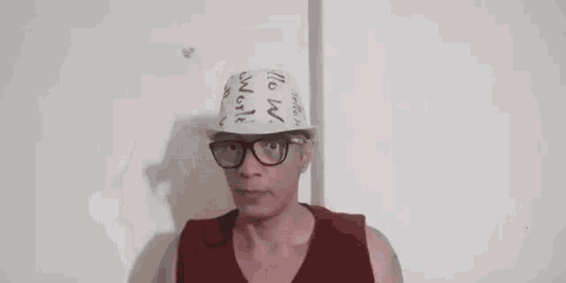 a man wearing a cone hat and glasses is standing in front of a wall .