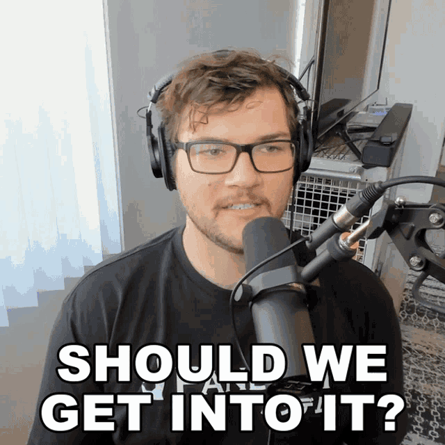 a man wearing headphones and glasses is talking into a microphone and says should we get into it