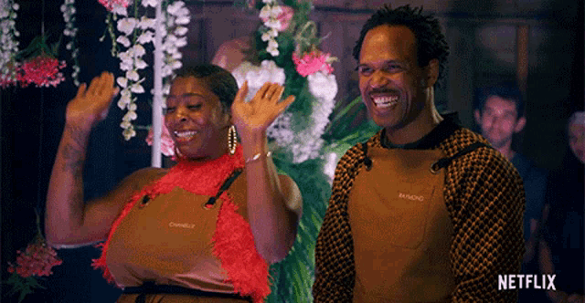 a man and a woman are standing next to each other in front of flowers and a sign that says netflix on it