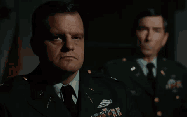 a man in a military uniform is standing next to another man in a military uniform .