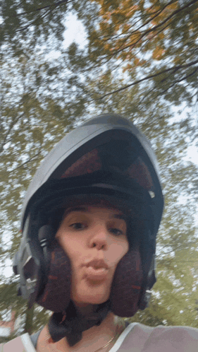a woman wearing a helmet blows a kiss at the camera