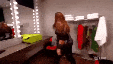 a woman is standing in a dressing room with a yellow suitcase and a mirror .