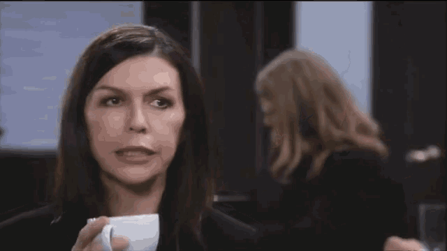a woman is drinking a cup of coffee in a room
