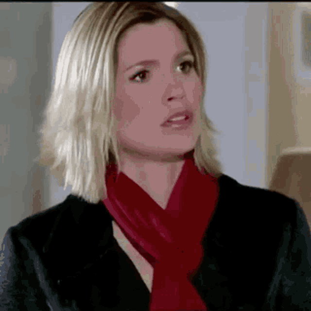 a woman wearing a red scarf and a black jacket .