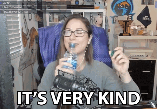 a woman drinking water in front of a microphone with the words " it 's very kind "
