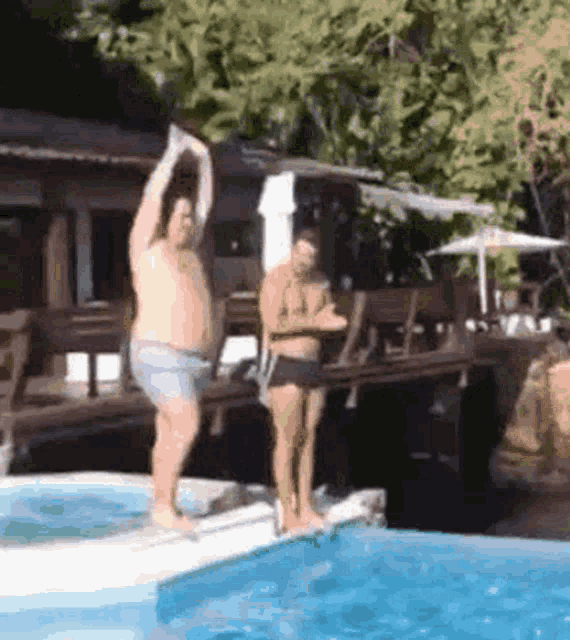 two men are jumping into a swimming pool while a woman watches