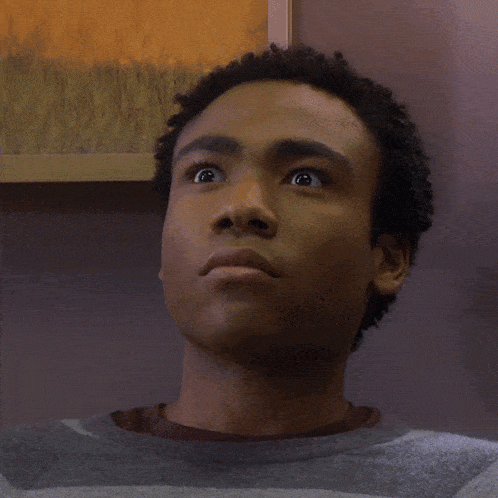a man with a surprised look on his face is wearing a grey sweater