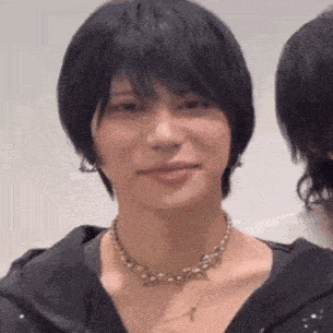 a close up of a woman wearing a necklace and a black jacket .