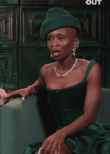 a woman wearing a green jacket and a pink shirt is sitting in a chair