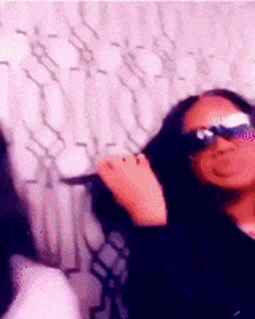 a woman wearing sunglasses is blowing a kiss at the camera