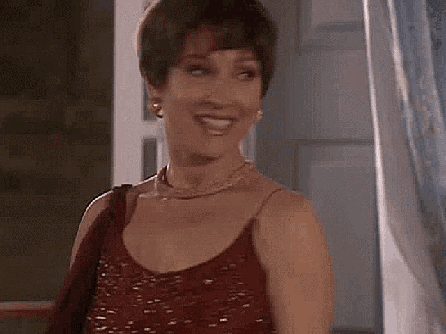 a woman wearing a red dress and a necklace is smiling .