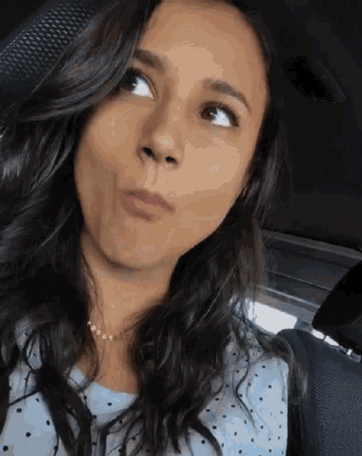 a woman making a funny face while sitting in the back seat of a car