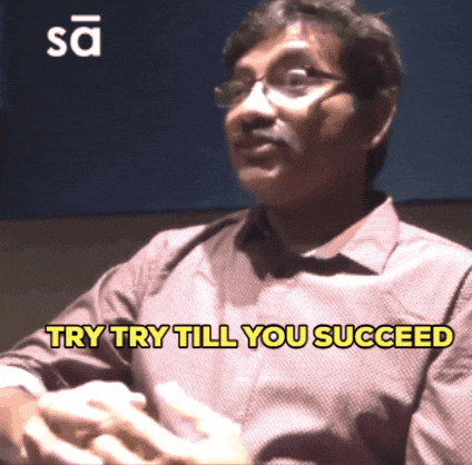 a man with glasses says try try till you succeed in yellow letters