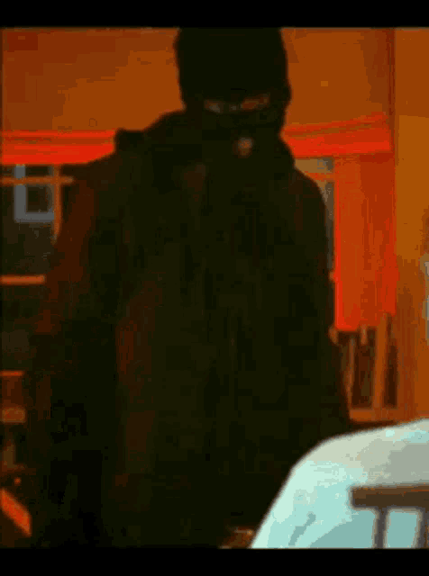 a man in a black mask is standing in a room .