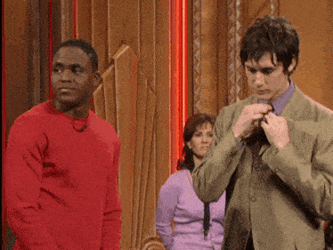 a man in a green suit stands next to another man in a red sweater