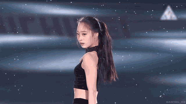 a woman in a black crop top stands on a stage