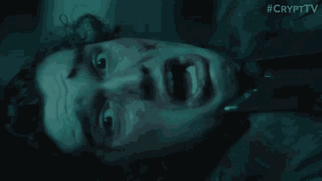 a man is laying on the ground with his mouth open in the dark .
