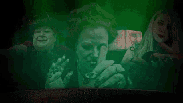 a group of women are standing in a dark room with a green background