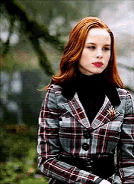 a woman with red hair is wearing a plaid jacket and a turtleneck .