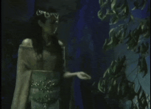 a woman in a green dress is holding a green glowing object in her hand .