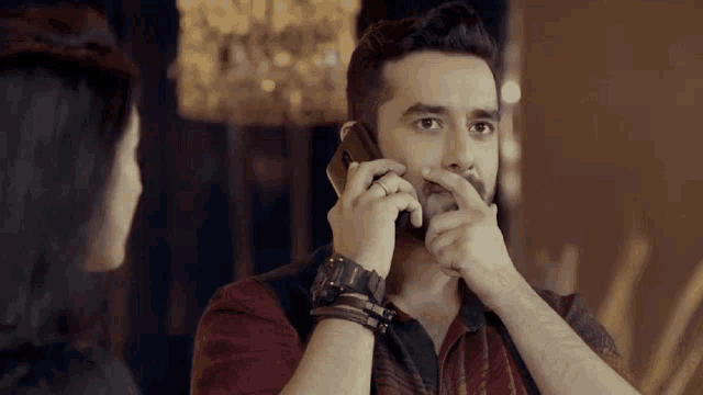 a man covering his mouth with his hand while talking on a phone
