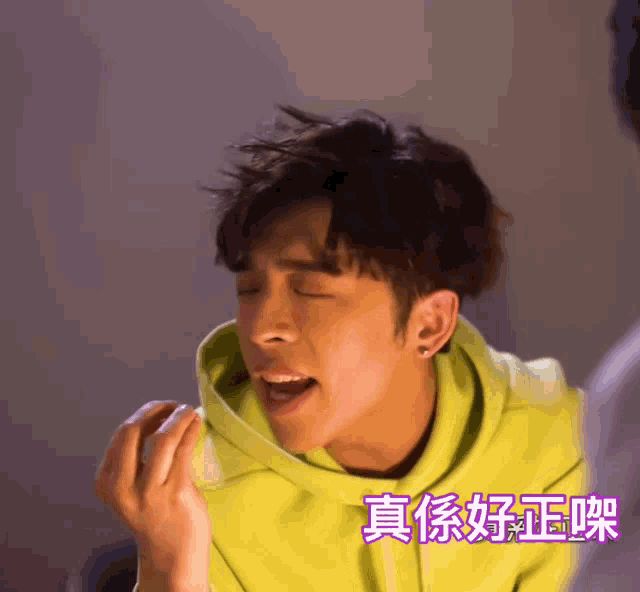 a young man wearing a green hoodie is making a face