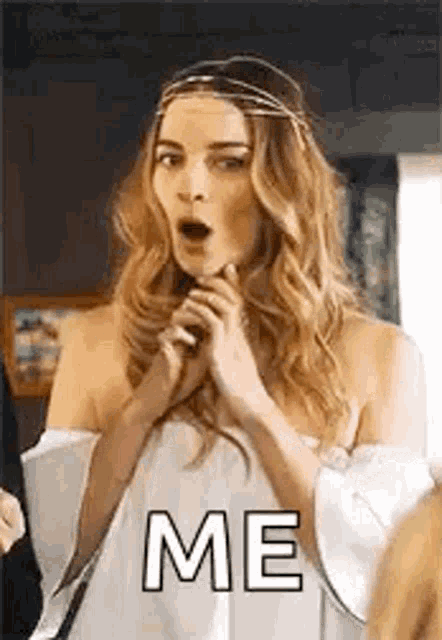 a woman in a white dress is making a surprised face while holding her hands to her face .