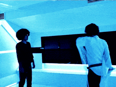 two people standing in a room with blue lights on the walls