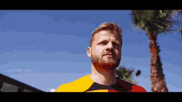 a man with a beard wearing a yellow and red shirt