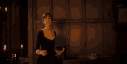 a woman in a black dress is standing in front of a clock .
