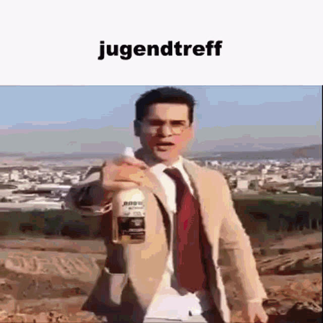 a man in a suit and tie is holding a bottle of alcohol in front of a city .