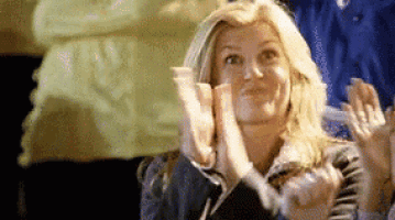 a woman is clapping her hands in front of a crowd .