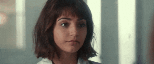 a close up of a woman 's face with short hair and bangs looking at the camera .