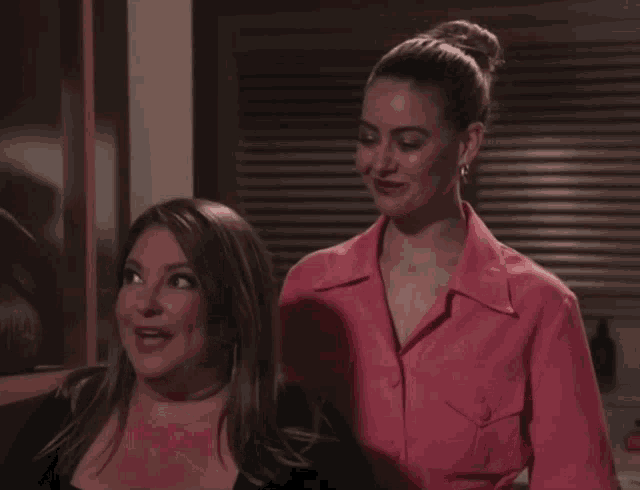 two women are standing next to each other and one is wearing a pink jacket