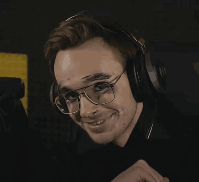 a man wearing glasses and headphones has a tattoo on his eyebrow