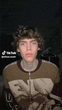 a young man with curly hair is wearing a sweater that says tiktok on it
