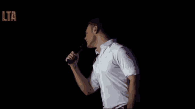 a man in a white shirt is singing into a microphone on a stage