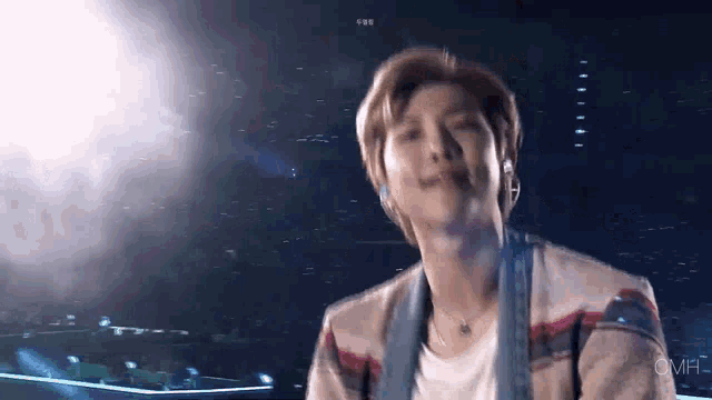 a man wearing a plaid jacket and a white shirt is standing in front of a stage .