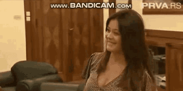 a woman is sitting on a couch in a living room smiling .