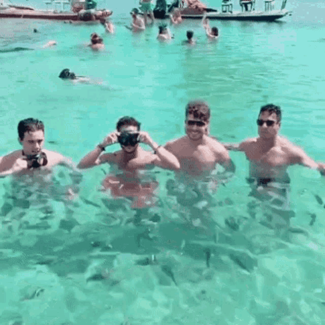 a group of men are swimming in the ocean and one of them is wearing a goggles