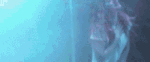 a blurry picture of a woman standing in a dark room with a blue background .
