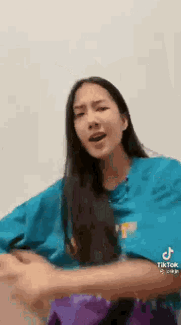 a woman in a blue shirt is making a funny face .