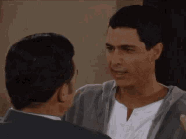 two men are standing next to each other and hugging each other in a room .