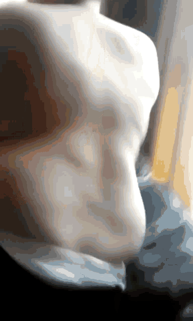 a blurry picture of a person 's torso with a yellow light behind them