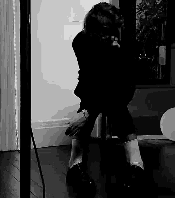 a black and white photo of a person kneeling on the floor .