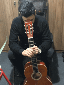 a man is playing an acoustic guitar with the letter t on the headstock