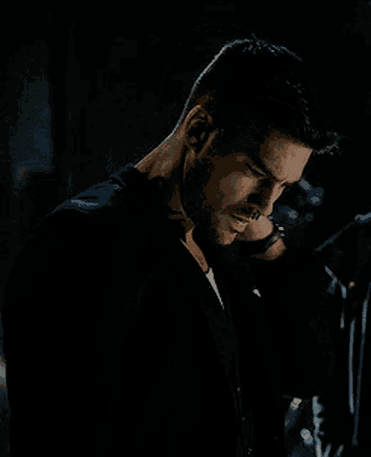 a man with a tattoo on his neck looks down in the dark