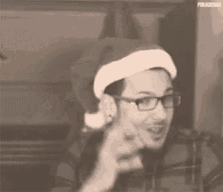 a man wearing a santa hat and glasses is pointing at something .