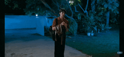 a man with a backpack is walking down a street at night .